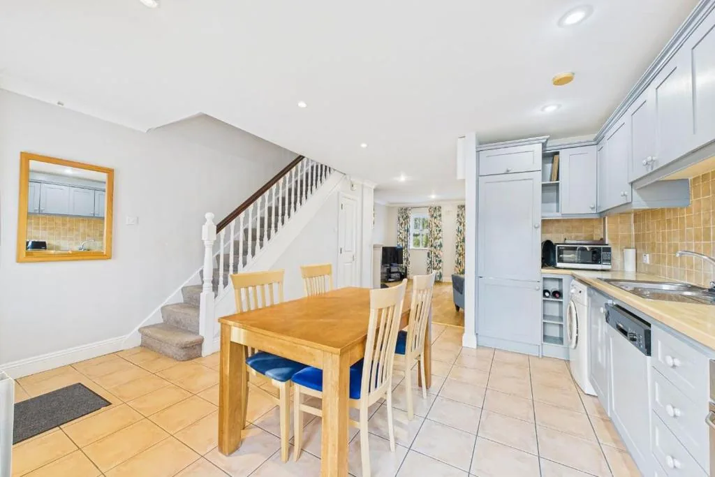 Dining table and kitchen with pale blue units and stairs