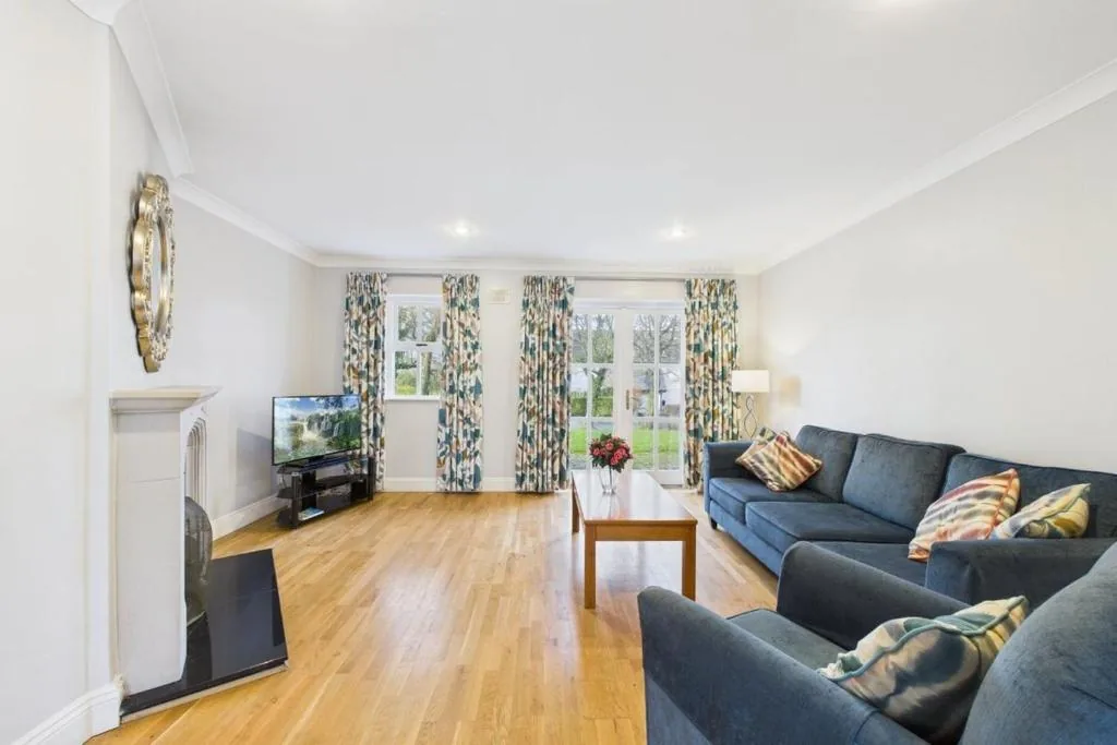 Bright living room with sofa, armchair, oak floor and open fireplace at Bolton Mews